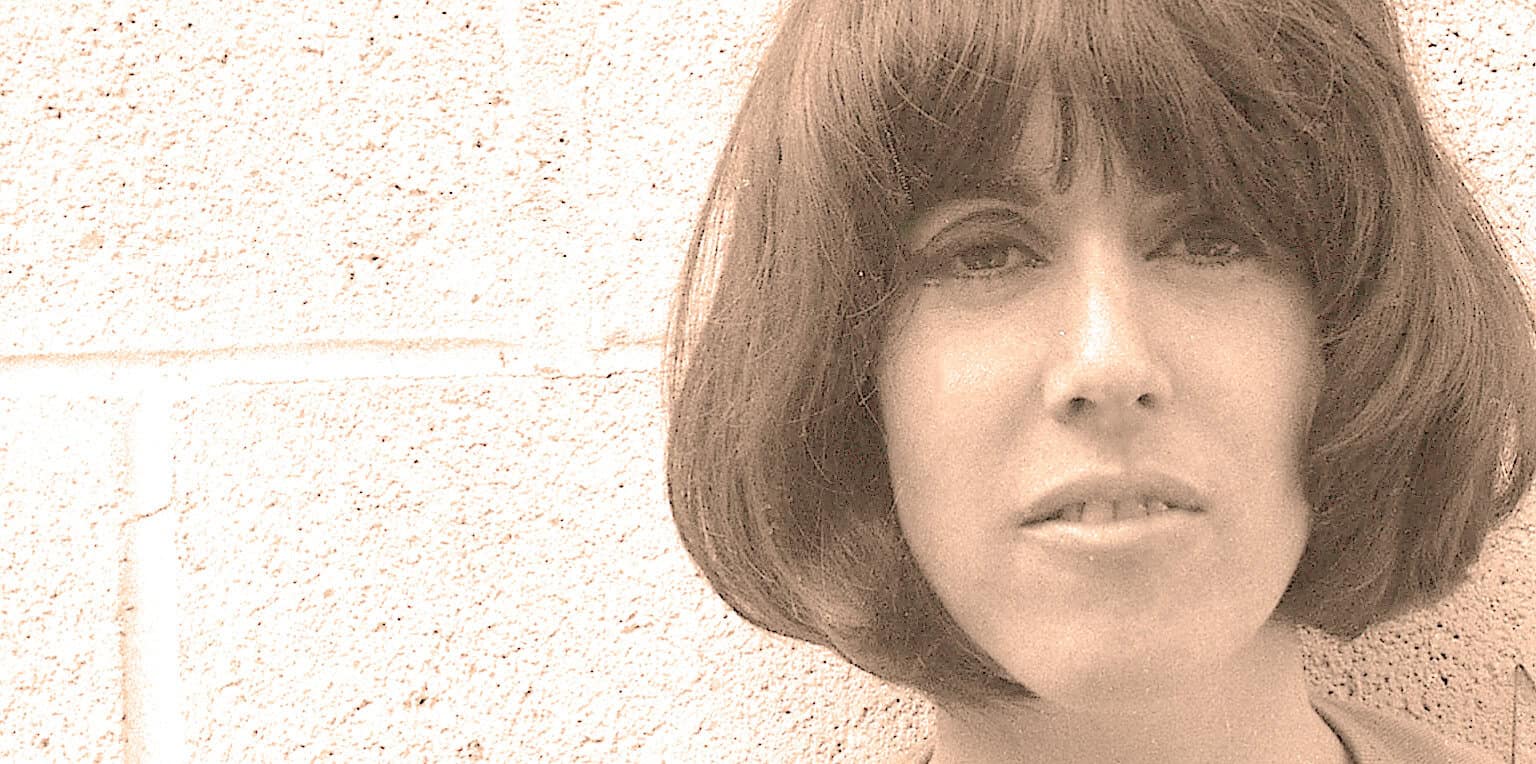 Profile of woman with short brown hair against brick wall, vintage style, nostalgic, history and music archive, classic portrait, Past Daily sound archive imagery.