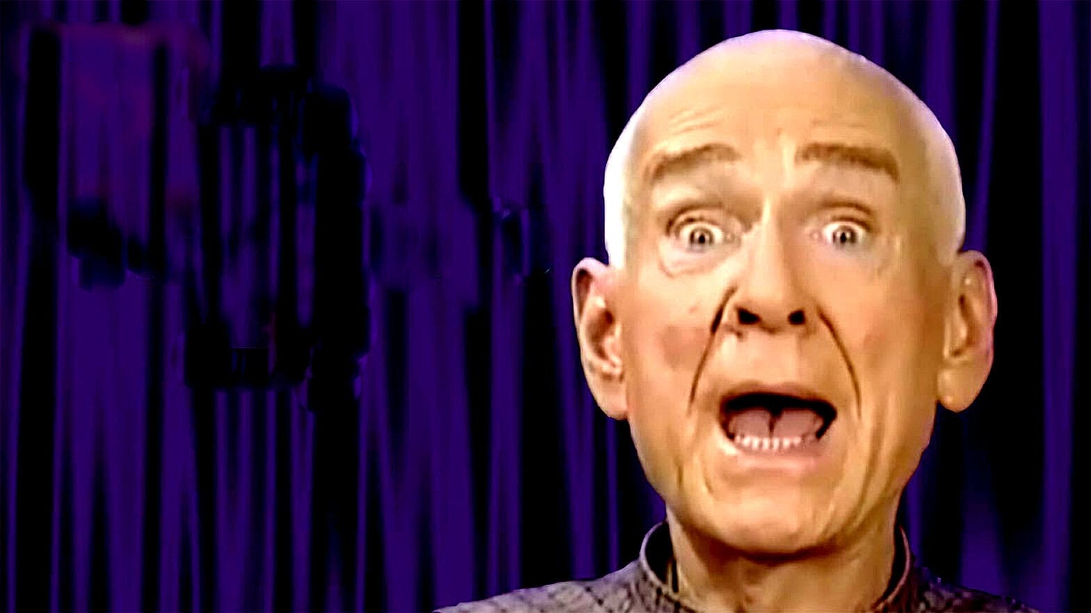 Evi altar, famous comedian with wide-open mouth on stage, expressive performance, comedy show, live entertainment, humor, stand-up comedy, vibrant purple background, Past Daily archives.