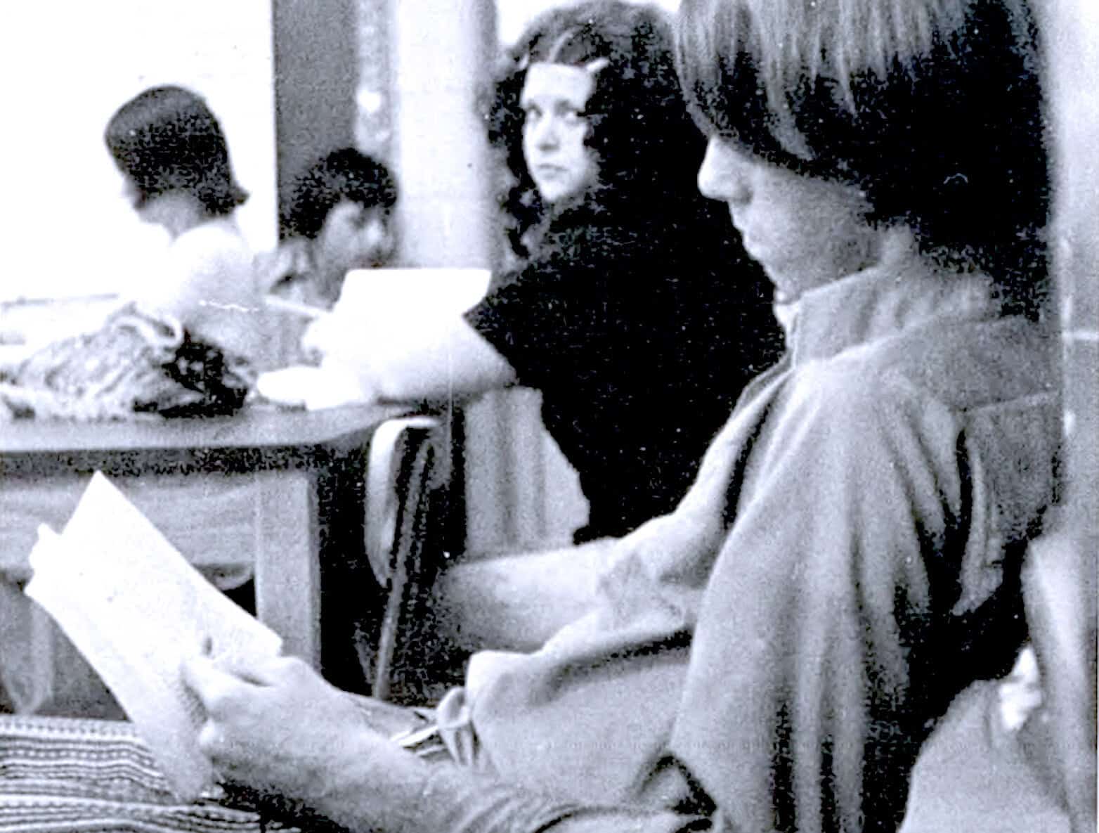 Historic black and white photo of young women reading printed materials in a social setting, highlighting news, history, and music archive preservation.