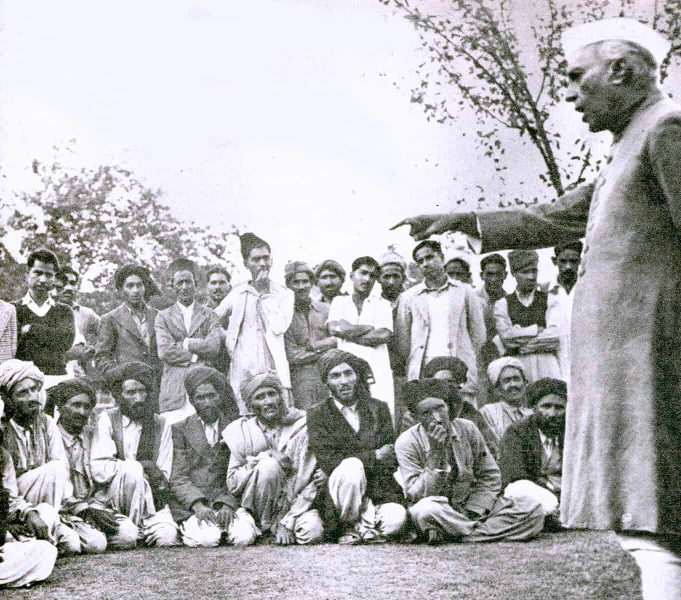 Historical black and white photograph of Mahatma Gandhi addressing a group of Indian villagers during India's independence movement, emphasizing peace and nonviolent protest strategies for social change, archival news and history image.