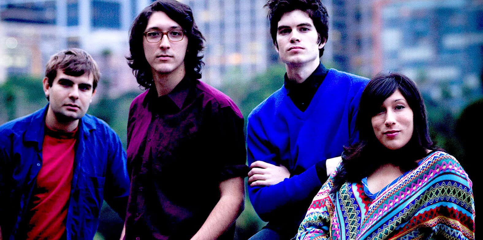 Past daily sound archive news history music band photograph of four young adults outdoors in an urban park setting colorful clothing and serious expressions.