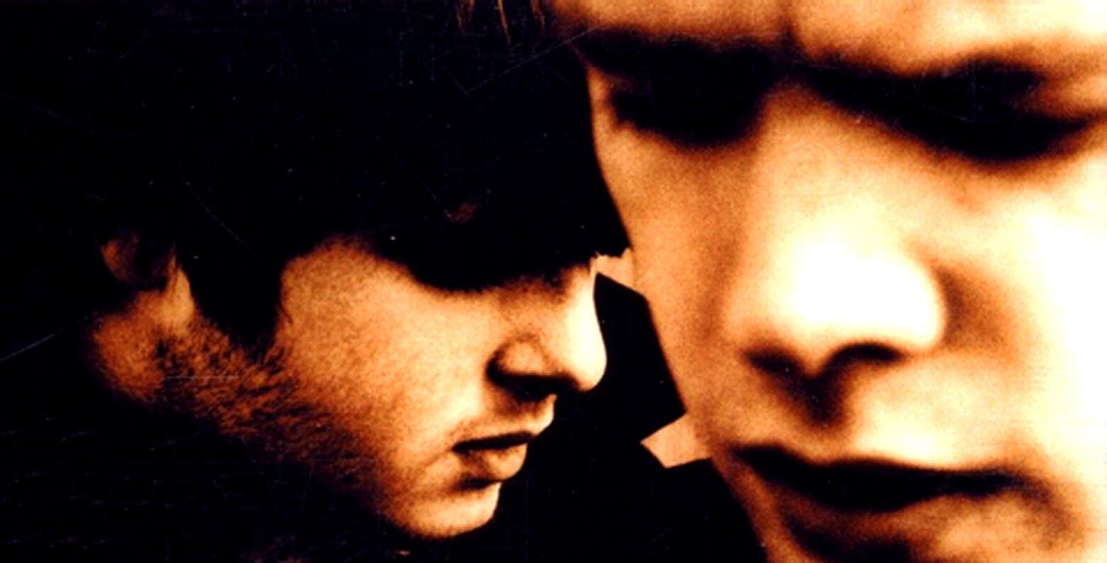 "Close-up of two young men with contemplative expressions, emphasizing nostalgia and music history, representative of Past Daily's sound archive of news, history, and music.".