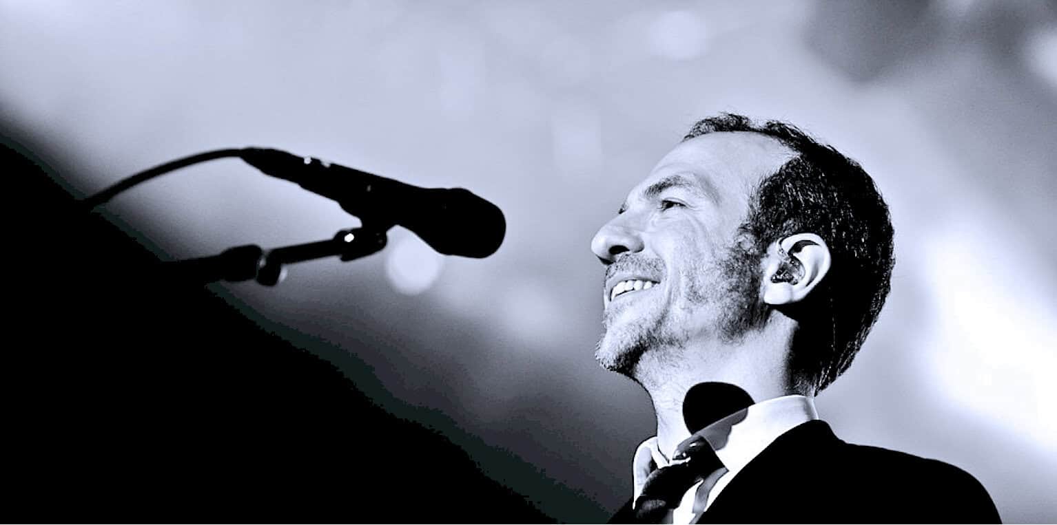 Historic musician performing on stage with microphone at Past Daily archive event, showcasing news, history, and music recordings.