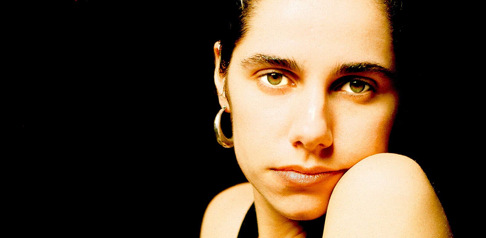 Close-up of a young woman with striking green eyes and hoop earrings, representing nostalgic music and news archiving, suitable for an image related to Past Daily’s sound archive of news, history, and music.