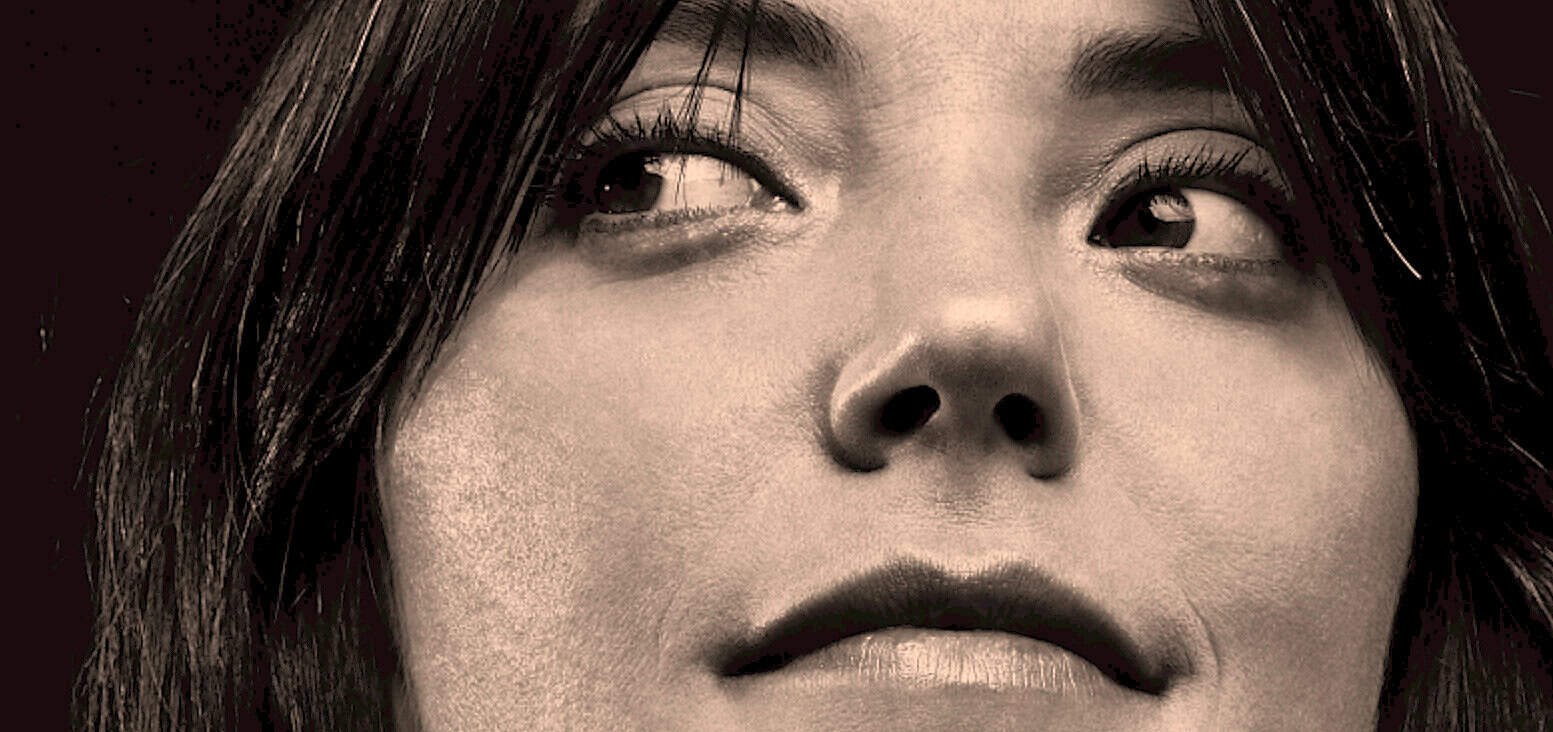 Close-up of woman's face with dark hair and expressive eyes, showcasing beauty and emotional depth, suitable for news, history, and music archives.