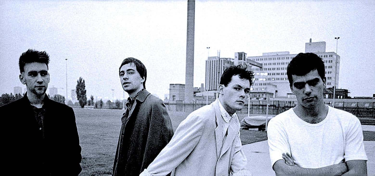 Urban skyline with four young men standing outdoors, representing a nostalgic or vintage vibe, ideal for a sound archive focused on news, history, and music.