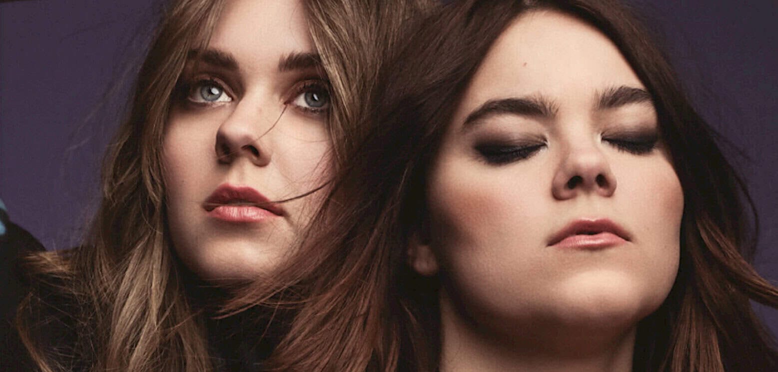 Spectacular women with flowing hair, makeup, and confident expressions, representing style and beauty, on dark background.