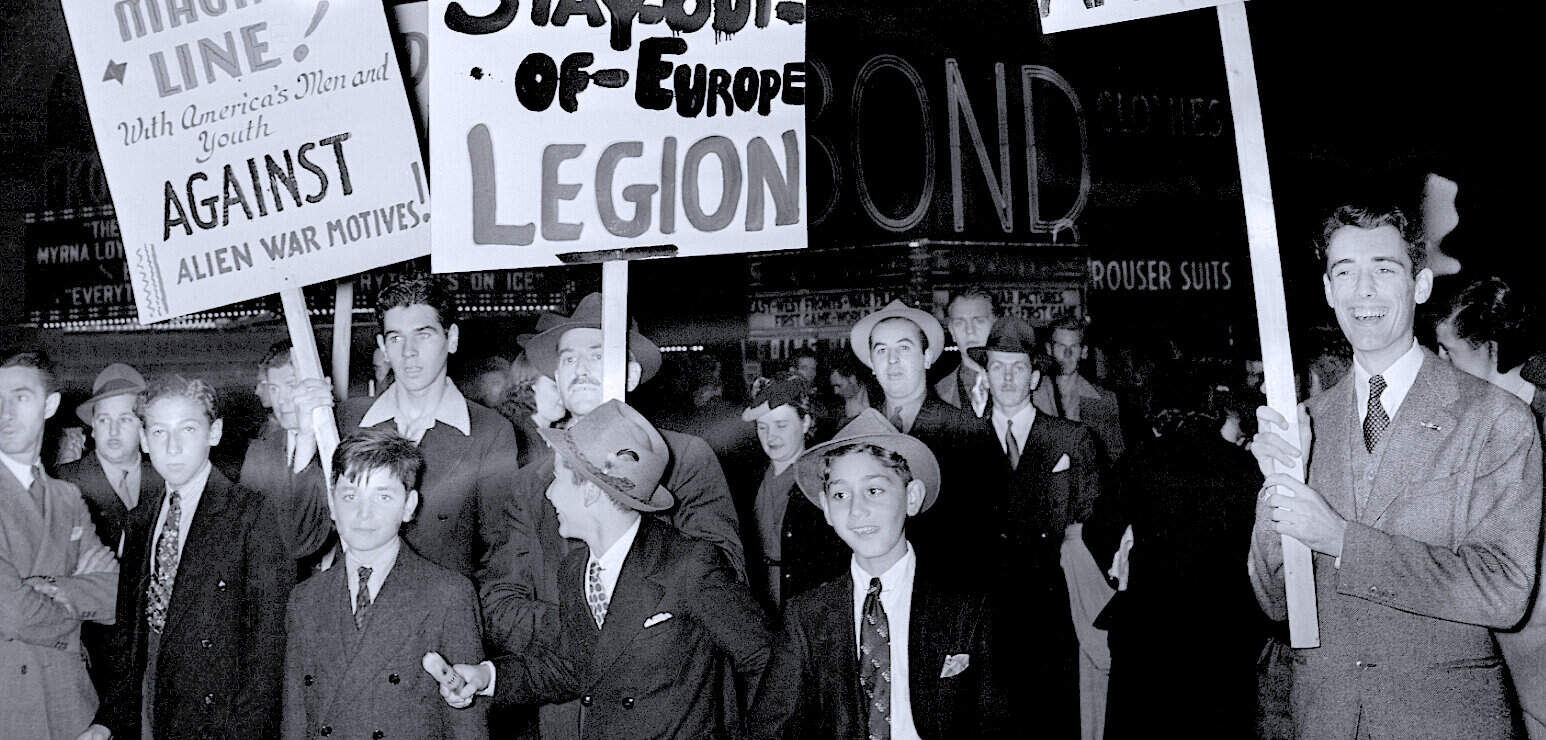 Protestors holding signs related to European legion and anti-war messages, vintage black-and-white photo illustrating historical news and social movements.
