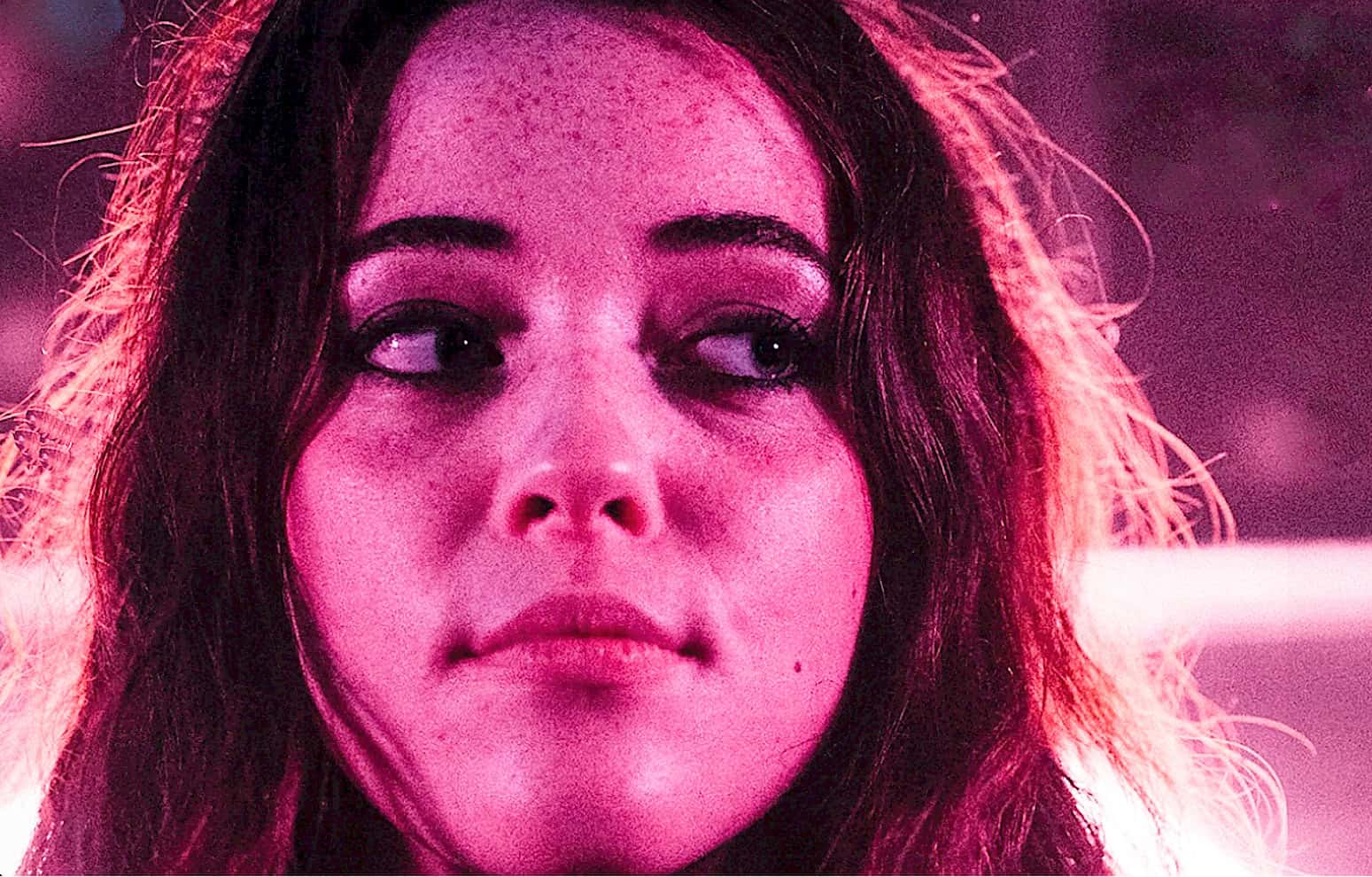 Close-up of a young woman with dark hair and expressive eyes, highlighting beauty and fashion, with a pink glow for artistic effect, ideal for music, news, and history archives.