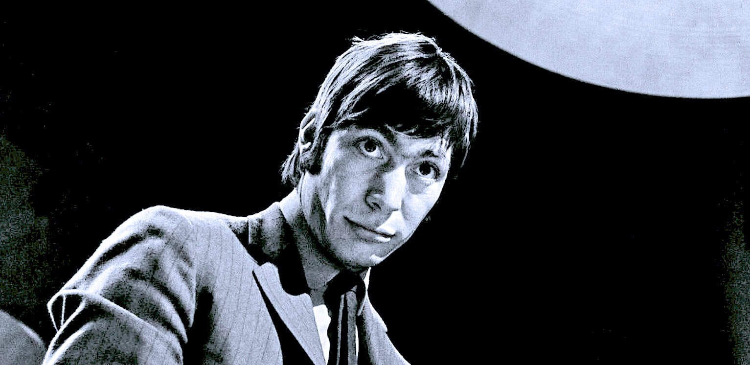 Vintage black-and-white photo of a man with short hair, wearing a striped jacket, representing the history and music archive focus of Past Daily.