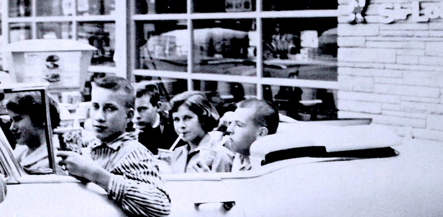 Children sitting in a vintage car, capturing a moment from mid-20th century, black and white photo, nostalgic childhood scene, classic automobile, historical family outing, iconic period image.