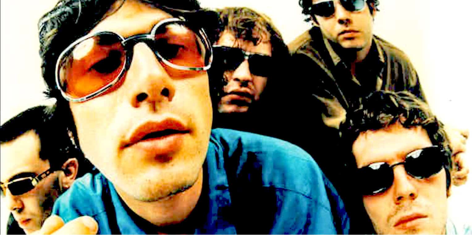 Band of young men wearing sunglasses, casual clothing, popular music group, retro style, energetic vibe, music fans, concert, youth culture, 90s fashion, musical performance, cool attitude, rock band, summer style, music archive, iconic music group, vintage photo, music history, band photography, music collection, past daily archive.