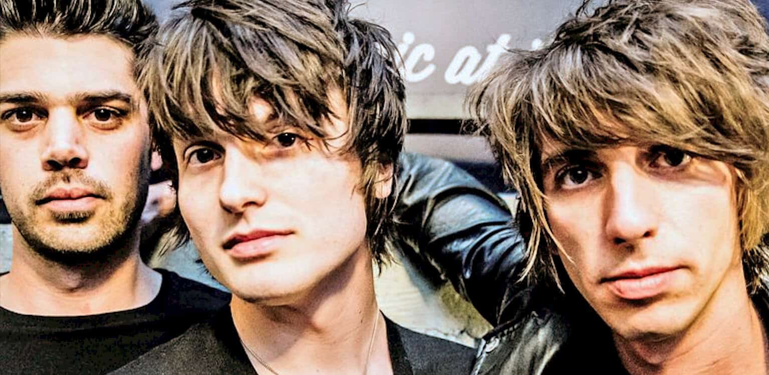 A close-up of a famous British rock band's lead singers with shaggy hairstyles at a music event. Iconic image emphasizing rock music, band members, and live performance energy.