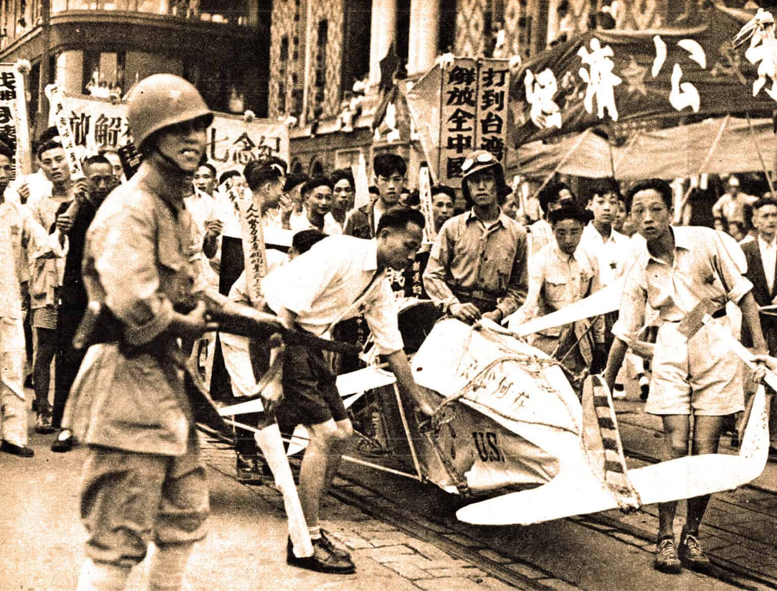 A historical black and white photograph of a protest or rally in an Asian city, featuring people holding banners and signs, with some individuals dressed in military-style clothing and helmets.