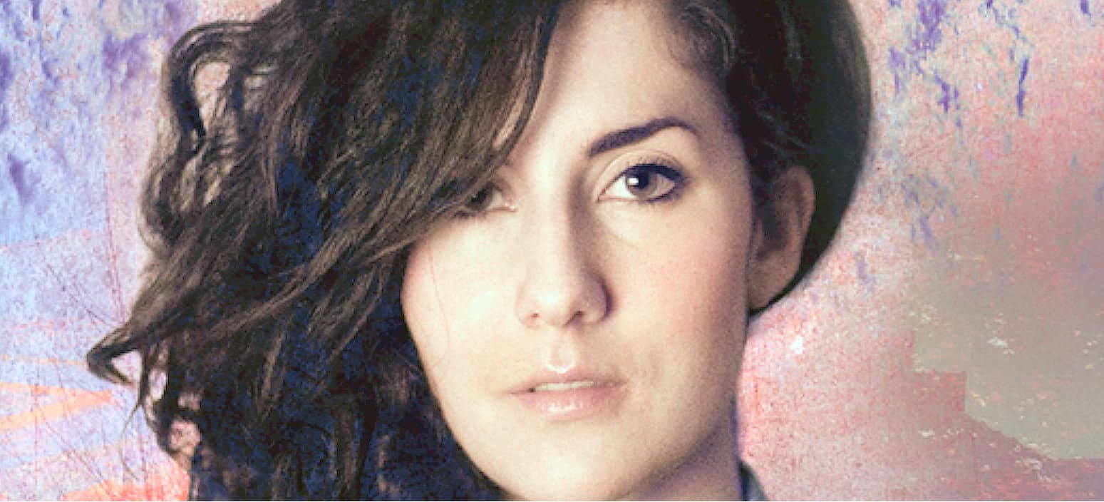 A woman with short brown hair and expressive eyes, showcasing a modern look focused on music, news, and history archives.