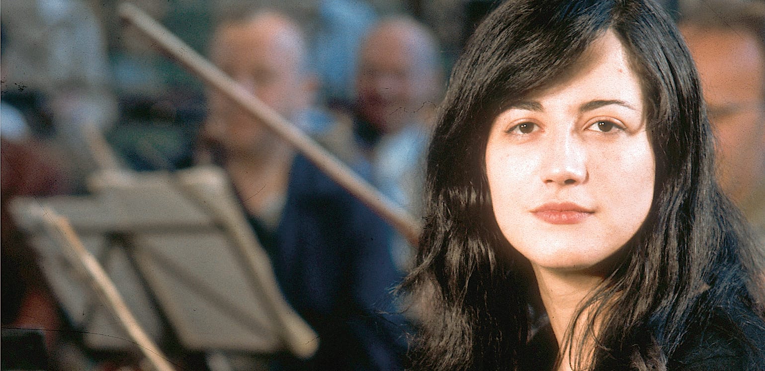 Young woman with long black hair, in a public space, representing news, history, and music archives.