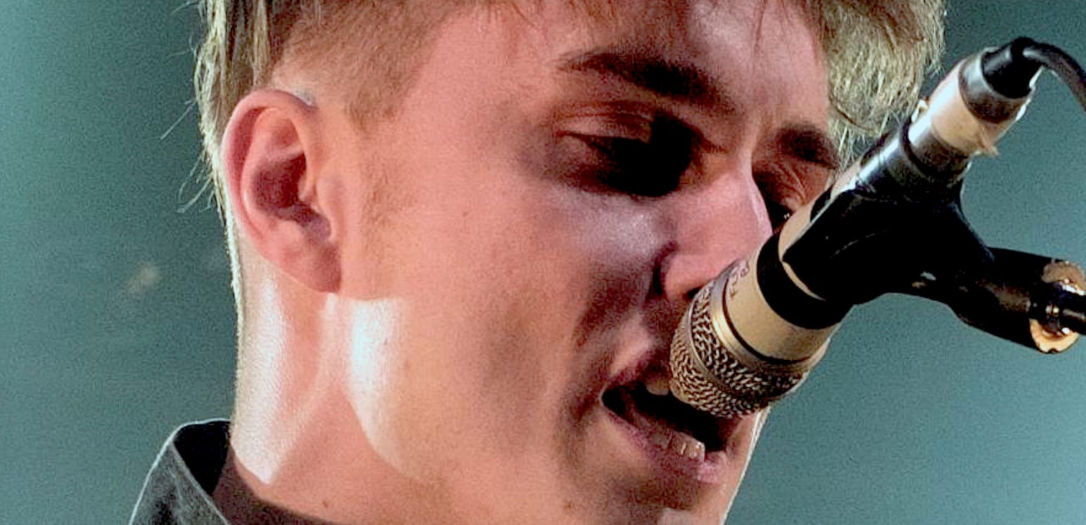 Close-up of a male singer performing with a microphone, capturing a live music moment for a sound archive showcasing music history, news, and cultural recordings.