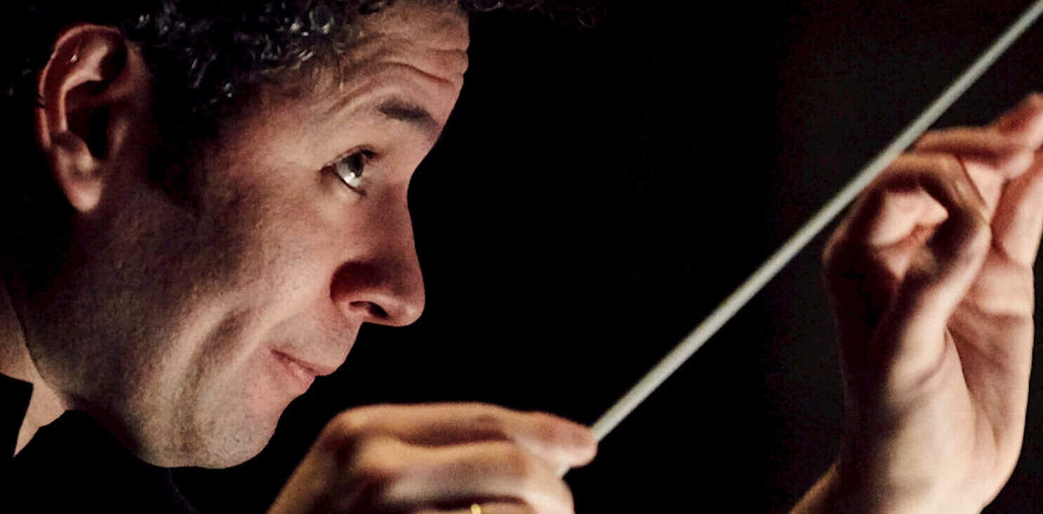 Slice of a man conducting an orchestra, focusing on his face and hand holding a baton, emphasizing music performance and conducting techniques.