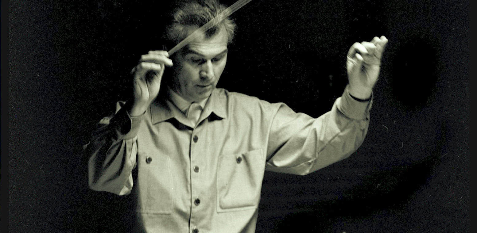 Studio conductor holding a baton in a music recording session, representing historical music archives and news sound recordings from Past Daily.