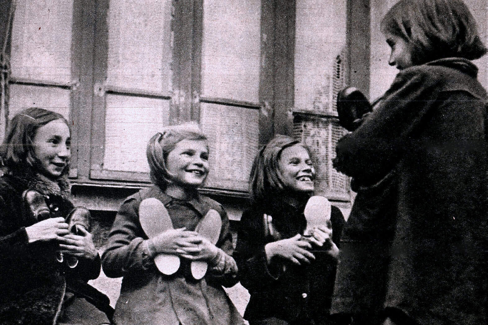 Children at a sound archive of news, history, and music listening to a woman talking, representing a historical moment of education and cultural preservation.