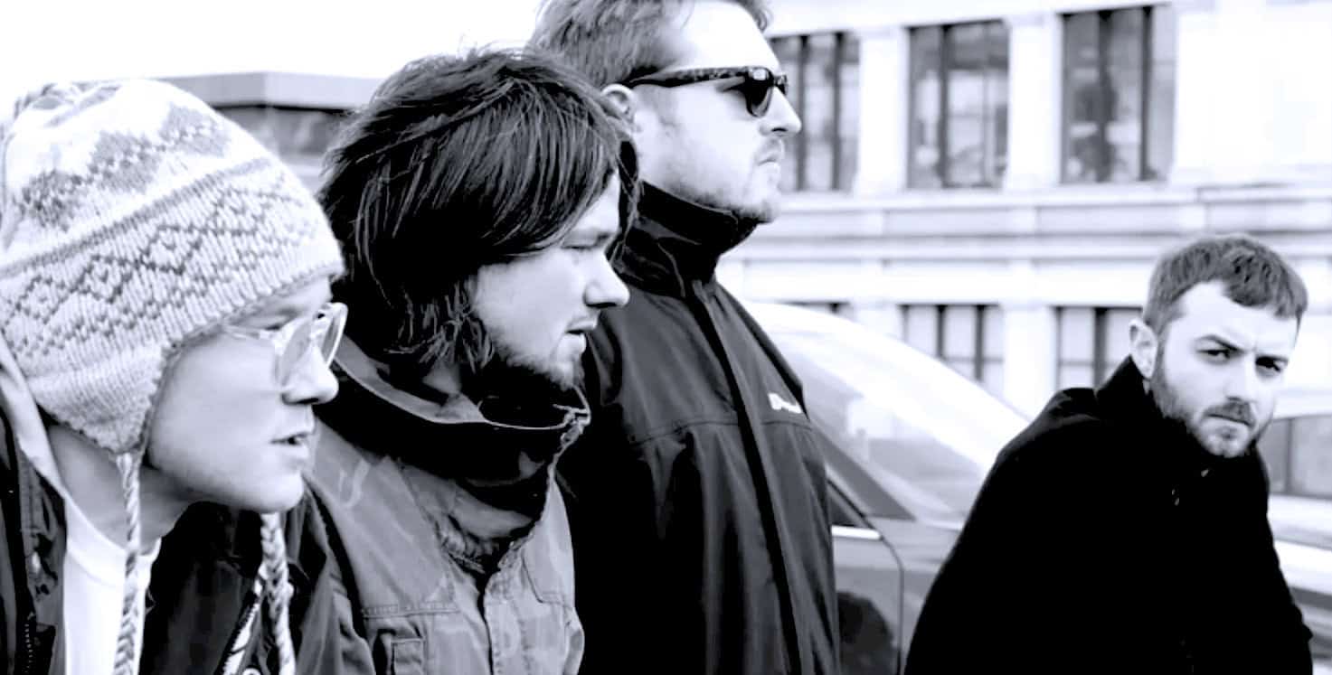 People standing outdoors in cold weather, urban setting, casual clothing, serious expressions, black and white photo, diverse group, street scene, documentary style, reflecting news and history themes, music influence, past daily archive, historic event scene.