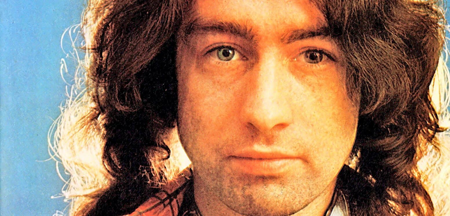 Close-up portrait of a 1970s rock musician with long wavy hair, blue background, symbolic of music history and nostalgic radio archive.