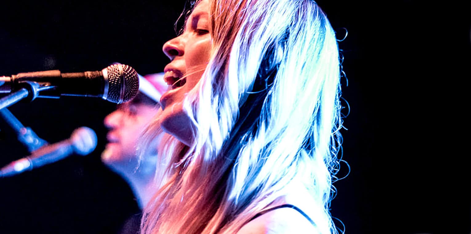 Vibrant image of a female singer performing with a microphone at a music event, showcasing live music, vocals, and stage lighting, emphasizing music history and entertainment.