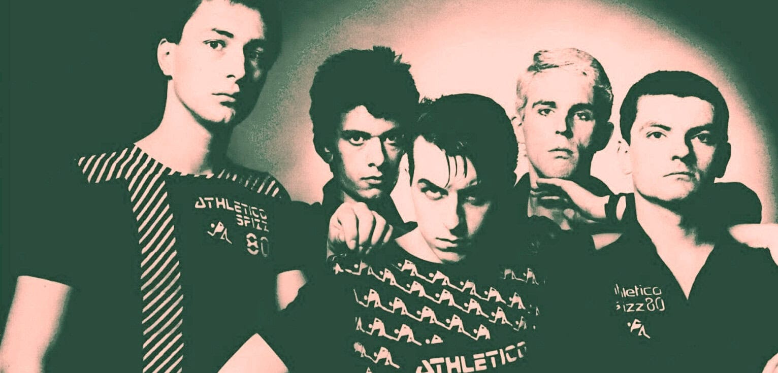 Young men in retro athletic apparel, representing a 1980s music or pop culture scene, captured in a stylized, vintage photo for nostalgic or historical content.