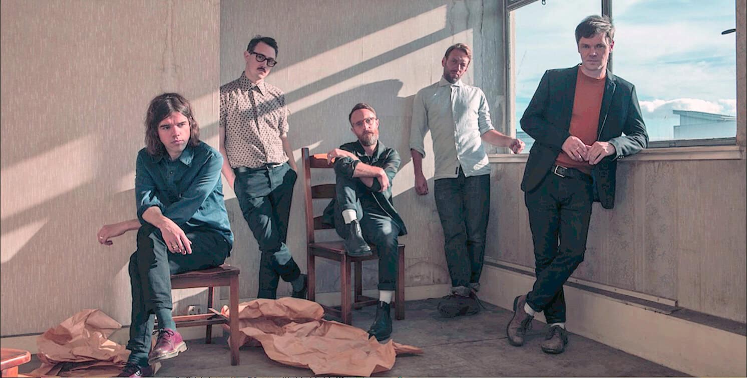 Vintage band members in an urban indoor setting, showcasing music history, with a focus on alternative and indie music culture, natural lighting adding artistic ambiance.