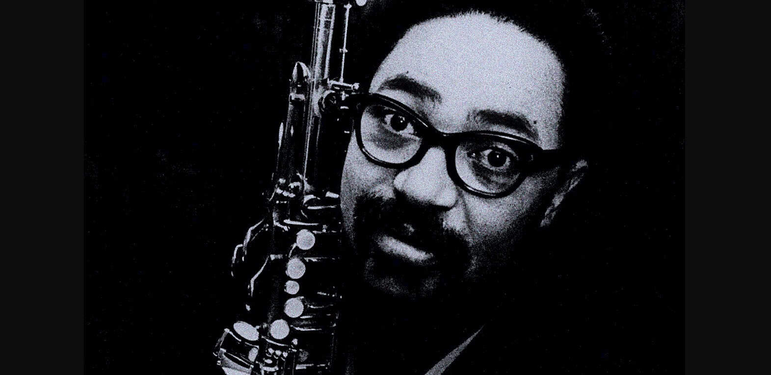 Saxophonist with glasses in black and white, symbolizing jazz and music history.