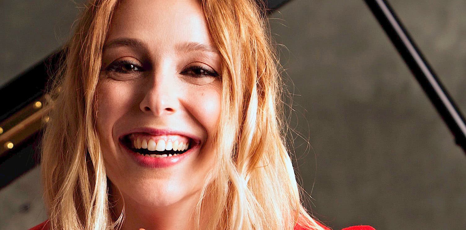 Smiling woman with long blonde hair, close-up portrait, joyful expression, ideal for music, news, and history archives, representing past audio recordings and sound history.