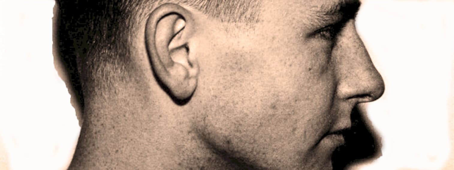 Close-up side profile of a man's face, emphasizing vintage photography style, expression, and historical research related to news, music, and history archives.