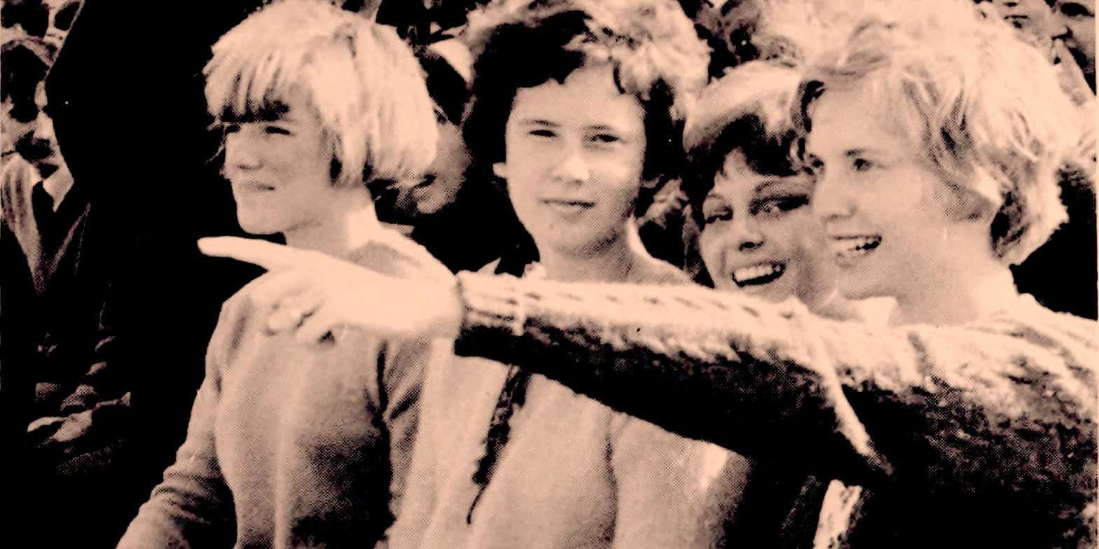 Kids pointing and smiling outdoors, capturing a joyful moment, vintage style for nostalgic news and music archive imagery.