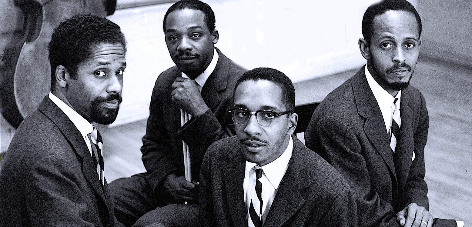 Black and white photo of four African American men in formal suits, capturing historical moments in music, news, and culture, reflecting the rich archive of past daily news and history.