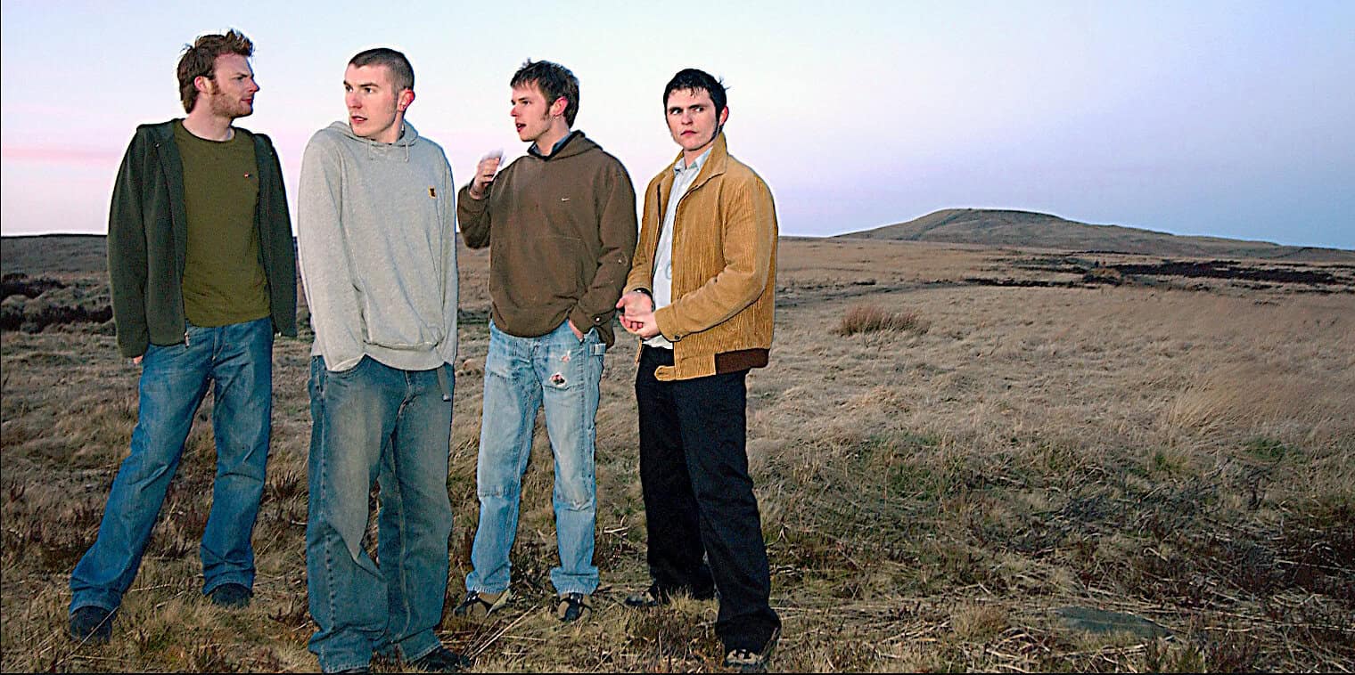 Young men standing in a vast open landscape during sunset, representing nostalgic music, history, and news archive themes of Past Daily.