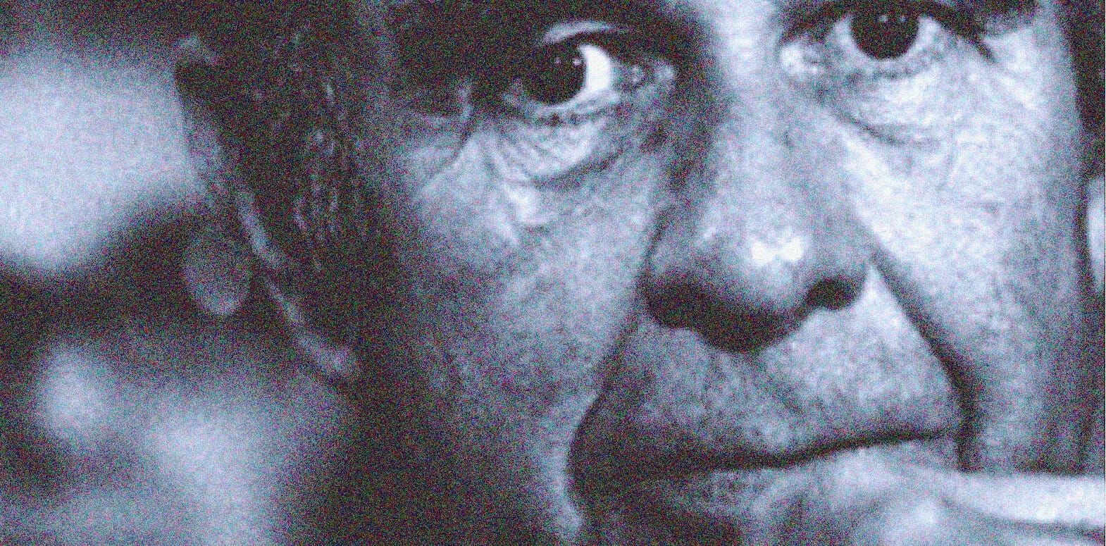 Close-up black and white photo of a mature man's face showing deep wrinkles and intense expression, emphasizing history, news, and music archive themes.