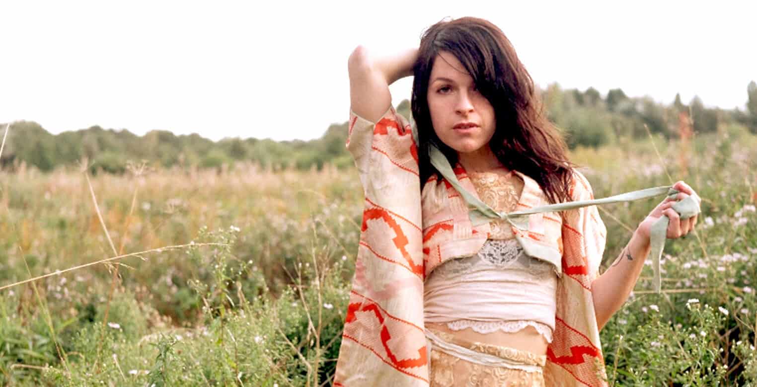 Vintage woman in a dress standing in a field of wildflowers, representing the nostalgic audio archive of news, history, and music from Past Daily.