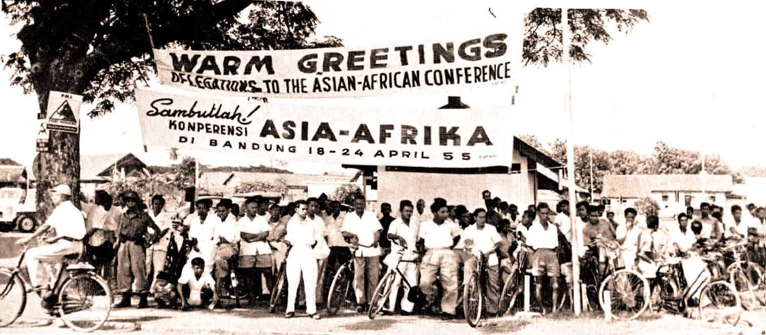 People gathering with bicycles in front of banners at the Asia-Africa Conference in Bandung, Indonesia, 1955, highlighting historical news, Asian-African diplomacy, and cultural heritage.
