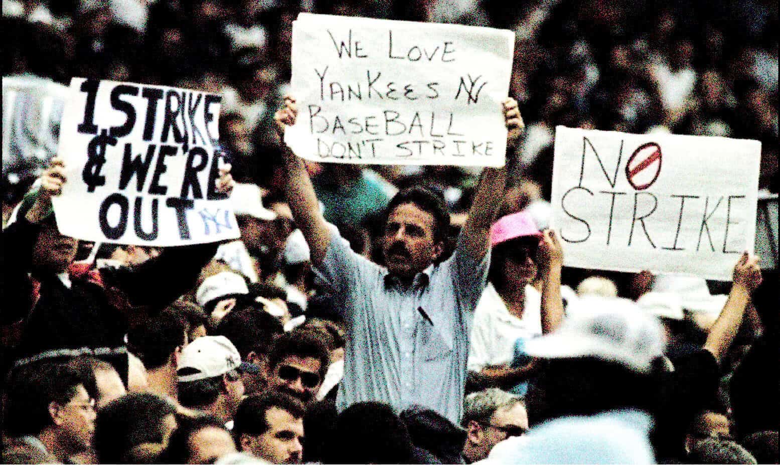 Yankees baseball protest signs in a crowd, emphasizing sports activism and community support during a strike rally.
