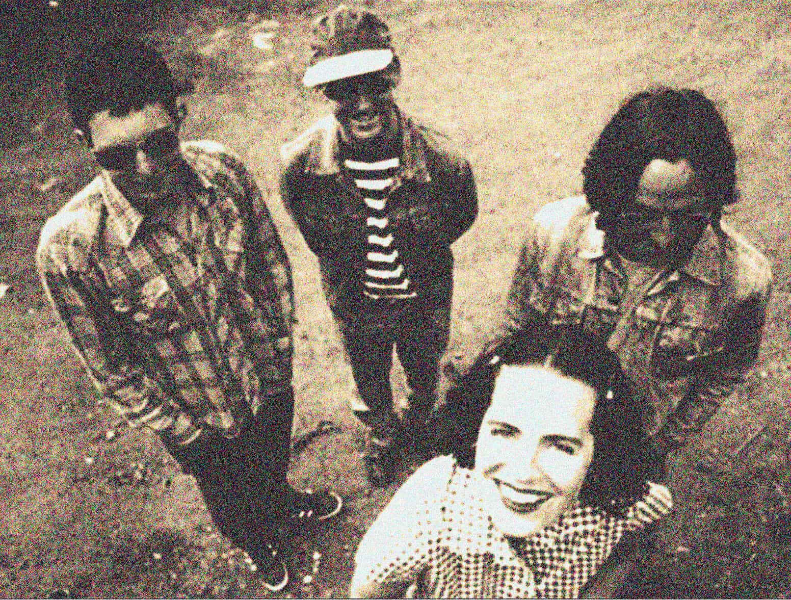 Vintage black and white photo of a diverse group of musicians and a woman smiling, capturing a moment of music, news, and cultural history for a sound archive related to Past Daily.