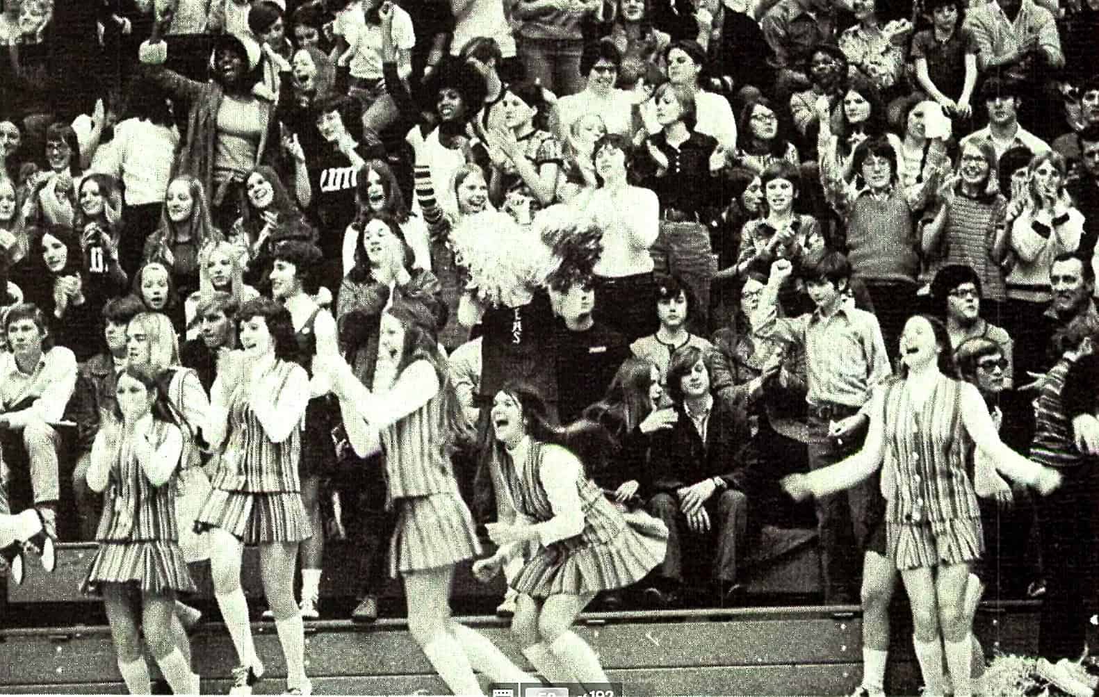 Vintage black and white photo of a lively dance performance with young women in striped skirts, audience in the background, capturing the vibrant music and cultural history featured on Past Daily.