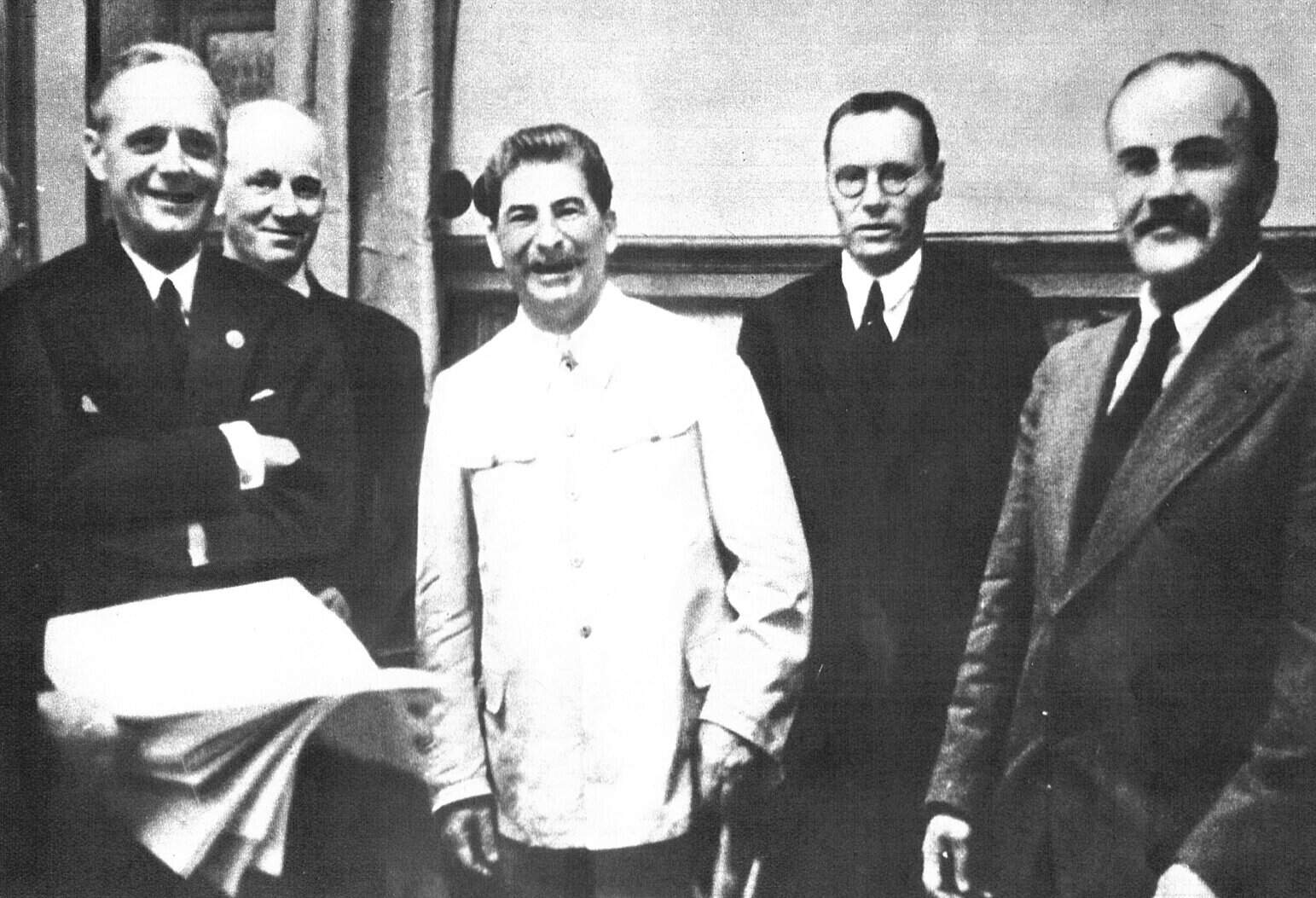 Historical black-and-white photo of five men in formal attire, representing news, history, for a sound archive of classic radio interviews and musical history.