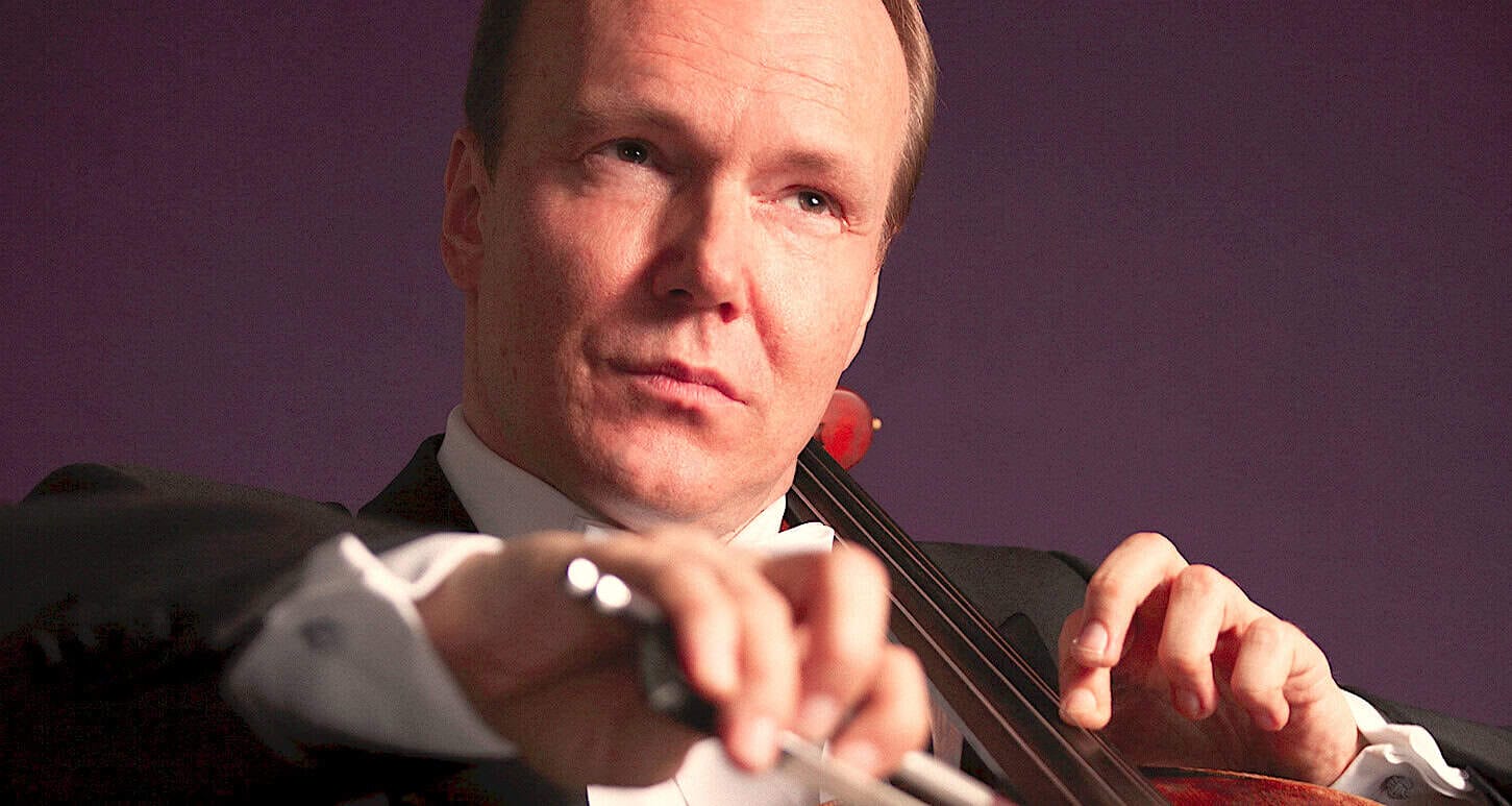 Renowned classical violinist playing his instrument in a professional performance setting, showcasing musical talent and artistry.