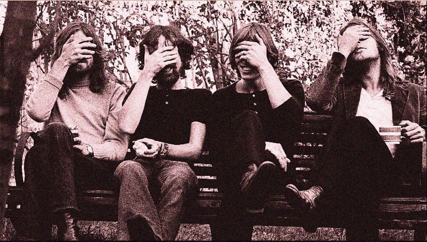 Vintage black and white photo of four friends sitting on a park bench, covering their faces, symbolizing casual moments, music, and social interactions, reflecting a nostalgic era.