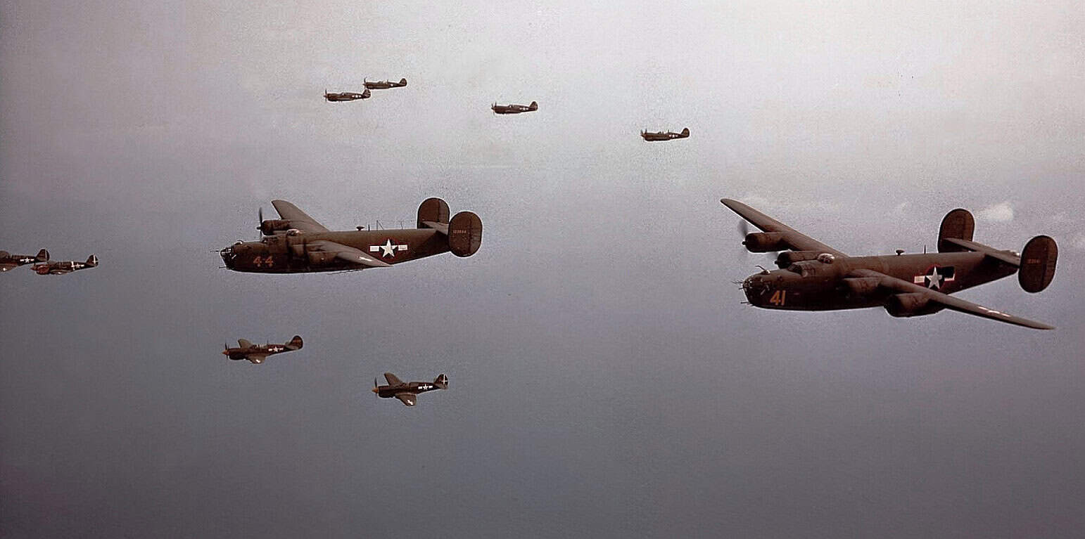 Vintage World War II B-24 Liberator bombers flying in formation during a historical military airshow.
