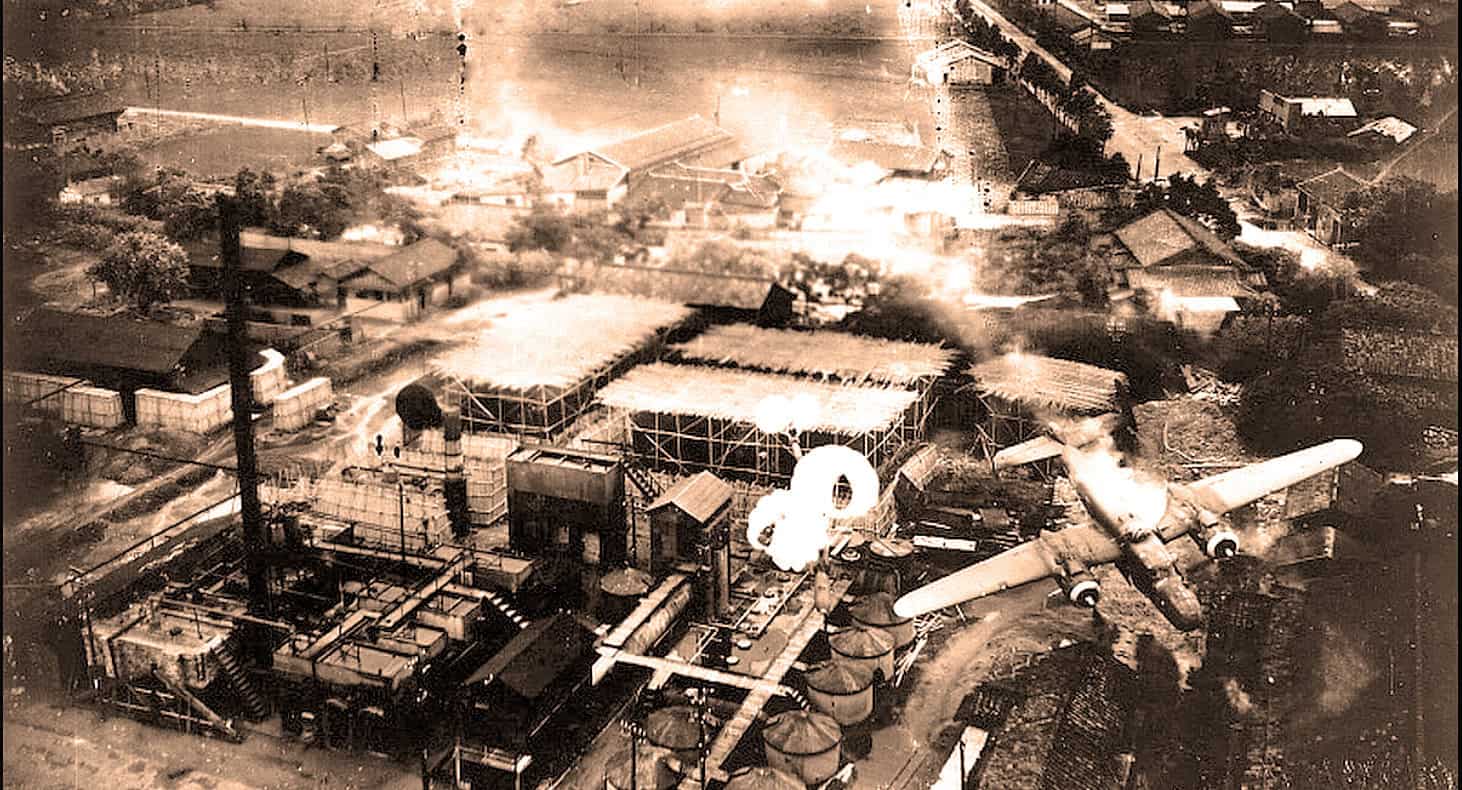 Aerial photo of WWII bombing raid on a residential and industrial area with smoke and explosions.