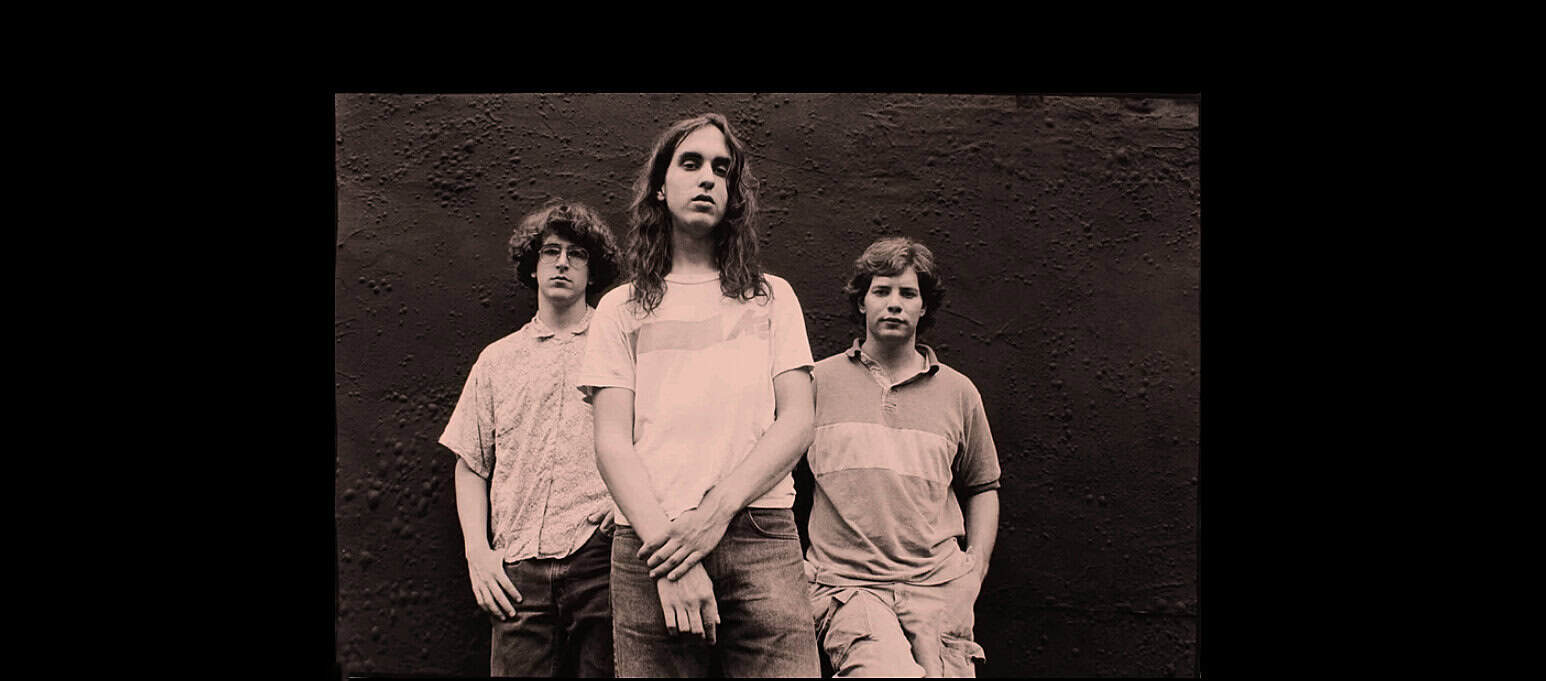 Band members standing against a textured wall, capturing a music scene related to historic sound archives, news, and music history.