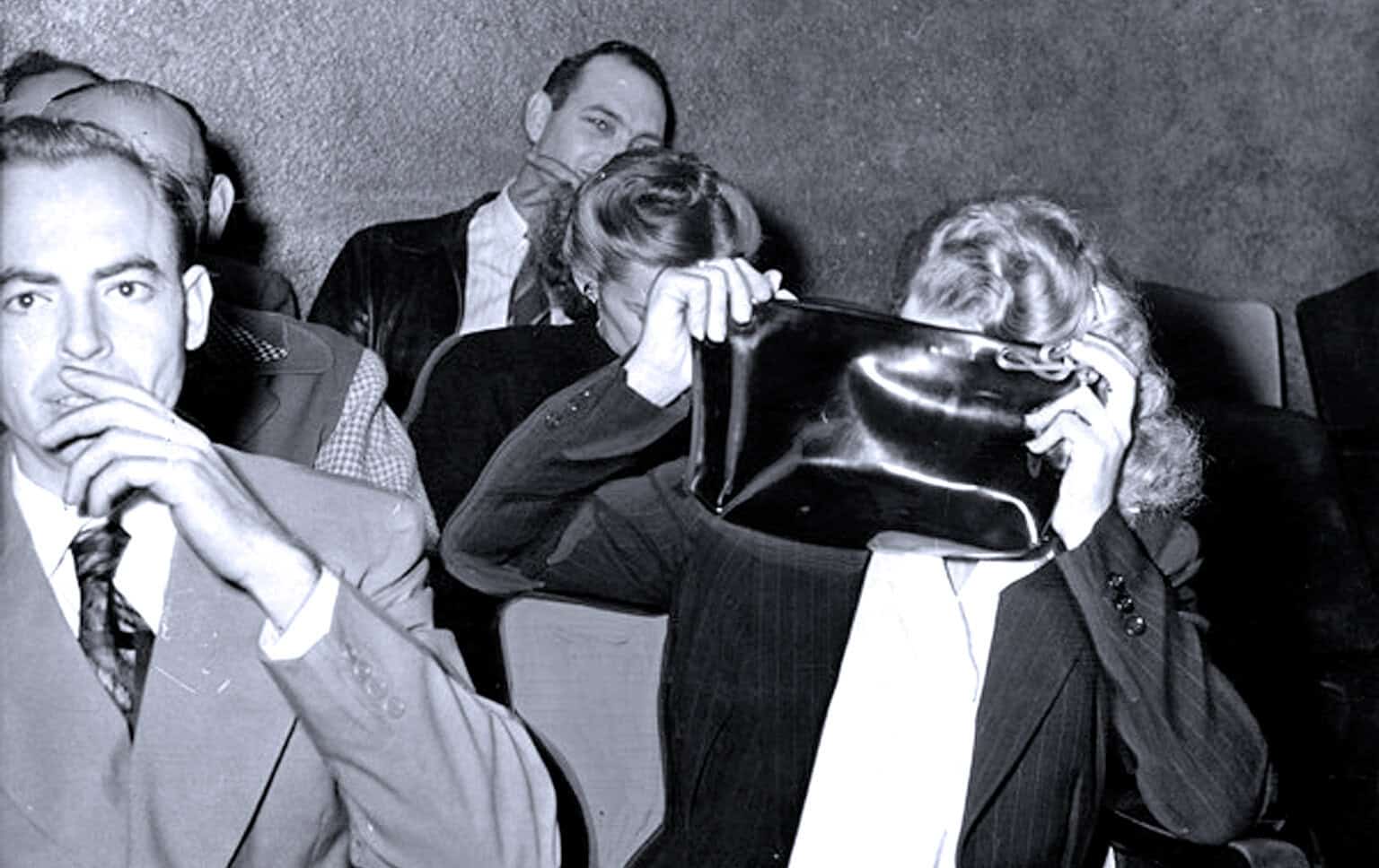 People attending a vintage news, history, and music archive event, some covering their faces with folders, capturing the essence of historical sound recordings and archival preservation.