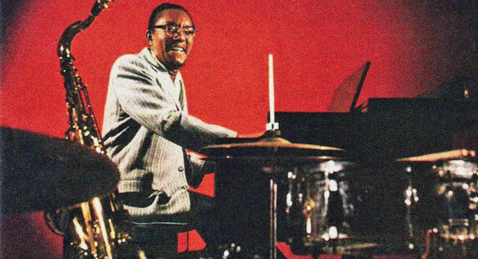 Vintage jazz musician playing drums and saxophone on red background, historical music archive, sound recording of jazz performances, news and history in audio format, Past Daily sound archive and music history collection.