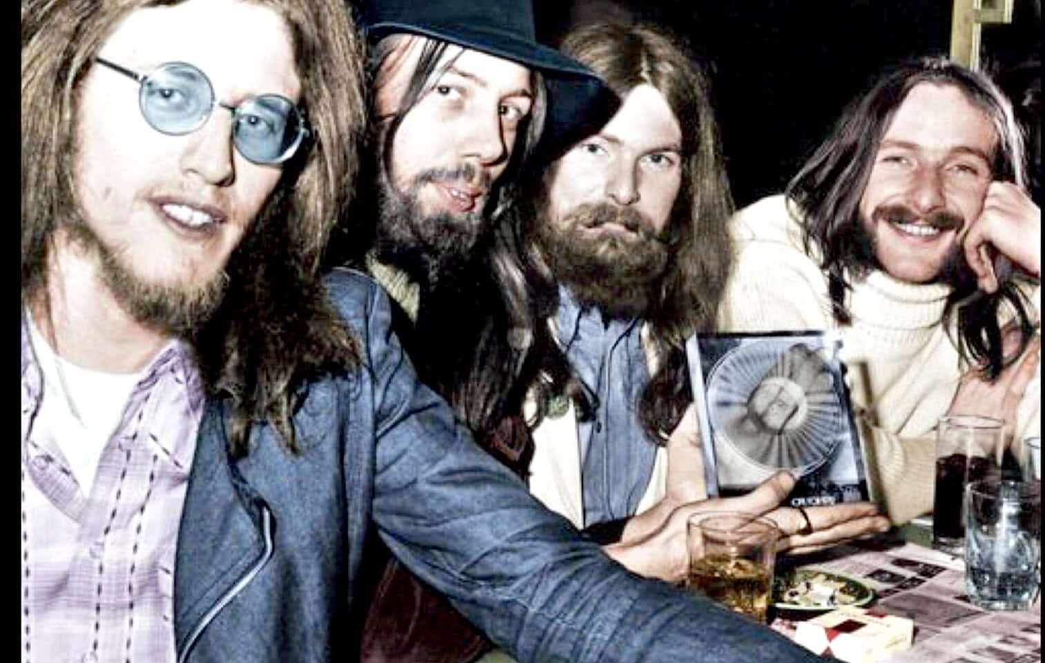 Retro rock band members enjoying a gig, showcasing classic 1970s style with long hair and beards, holding a vintage fan and drinking beverages, capturing the essence of music history and nostalgia.